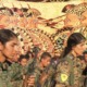 Los combatientes de YPG e YPJ están firmes (primer plano), el jarrón Chigi representa falanges de hoplitas (fondo).